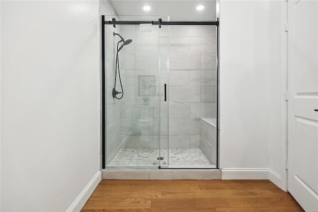 bathroom featuring a shower with shower door and hardwood / wood-style floors