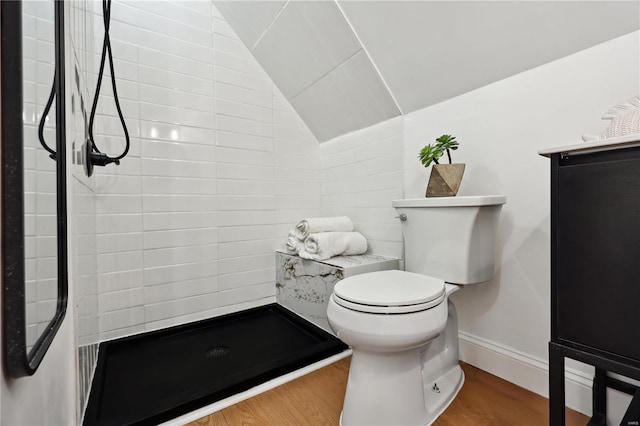 bathroom with vaulted ceiling, toilet, hardwood / wood-style floors, and a shower