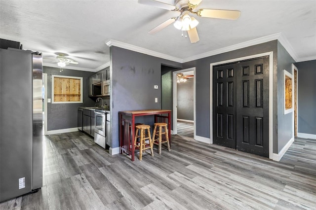 kitchen with crown molding, sink, wood-type flooring, and appliances with stainless steel finishes