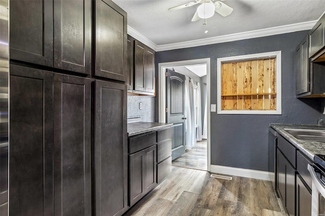 kitchen featuring ceiling fan, crown molding, light wood-type flooring, and sink