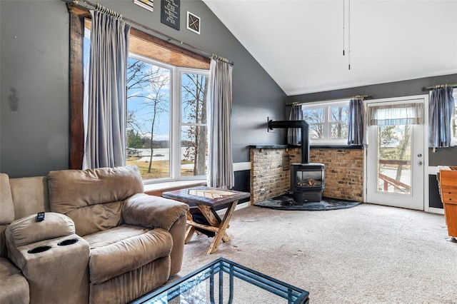 living room with a wood stove, carpet floors, a healthy amount of sunlight, and vaulted ceiling