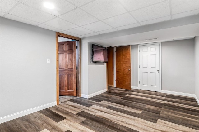 empty room with dark hardwood / wood-style floors and a drop ceiling