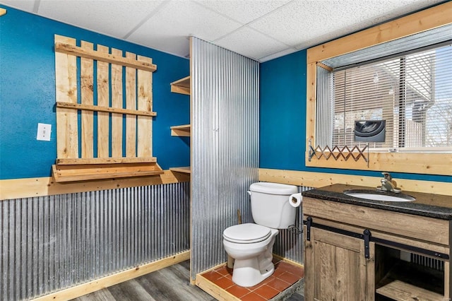 bathroom with vanity, a paneled ceiling, hardwood / wood-style flooring, and toilet