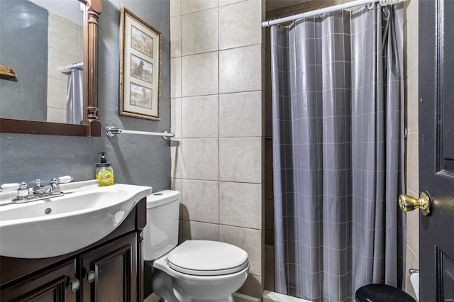 bathroom with vanity, curtained shower, toilet, and tile walls