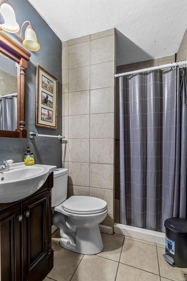 bathroom with a shower with curtain, tile patterned flooring, toilet, vanity, and tile walls