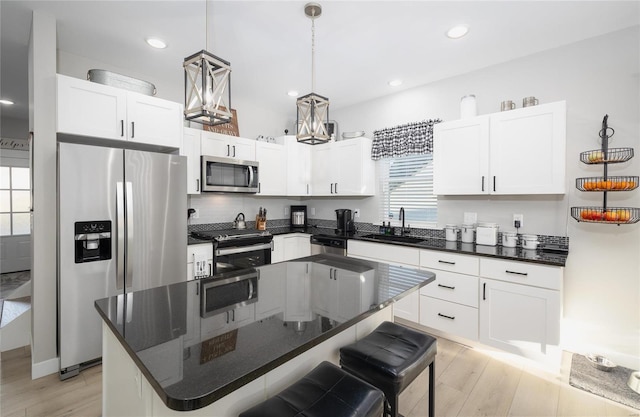 kitchen with stainless steel appliances, a breakfast bar, a sink, and light wood-style flooring