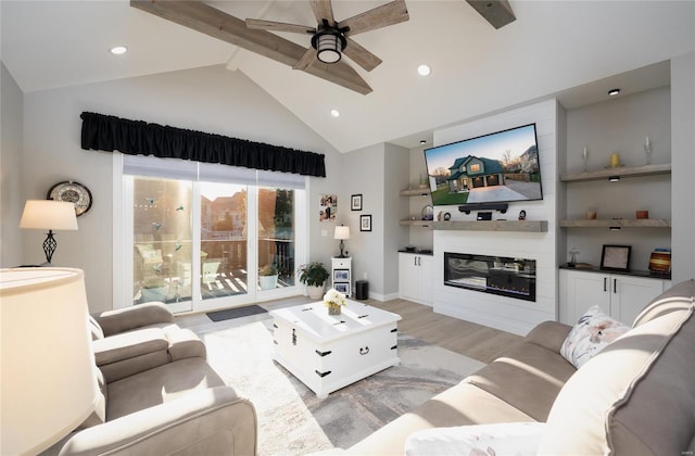 living room with high vaulted ceiling, ceiling fan, light wood-type flooring, beam ceiling, and a large fireplace