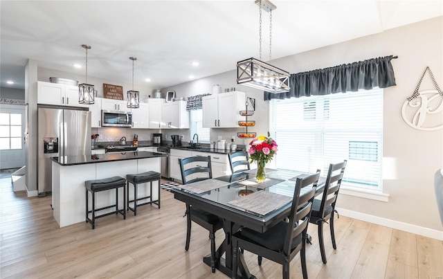 dining space with sink, a healthy amount of sunlight, and light hardwood / wood-style floors