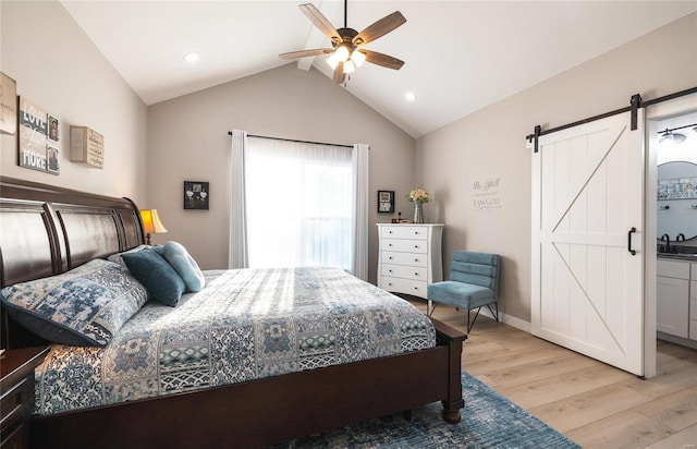 bedroom with sink, vaulted ceiling, ceiling fan, a barn door, and light hardwood / wood-style floors