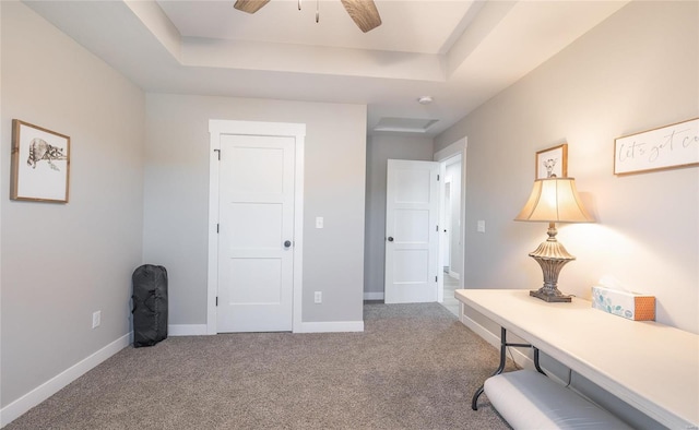 office area featuring carpet flooring, ceiling fan, and a tray ceiling