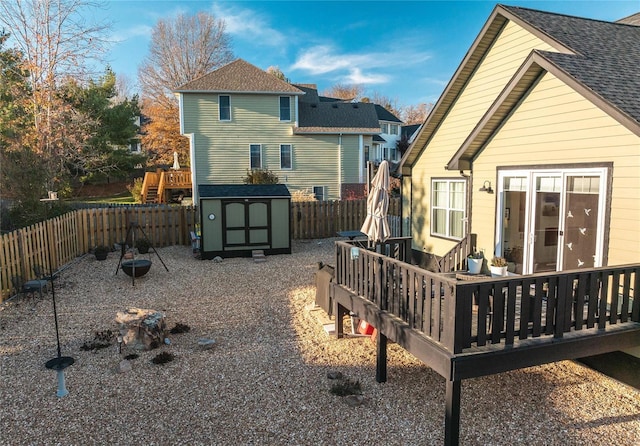 back of property featuring a storage shed, a deck, and an outdoor fire pit