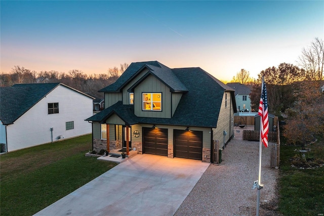 view of front facade featuring driveway, stone siding, board and batten siding, a front yard, and a garage