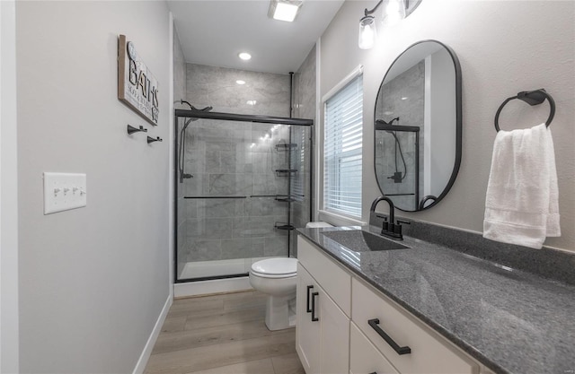 full bath with a stall shower, toilet, vanity, and wood finished floors