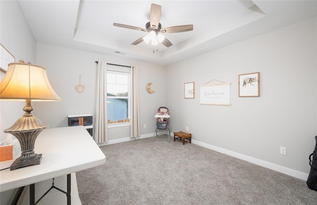 office featuring visible vents, baseboards, ceiling fan, a raised ceiling, and carpet flooring