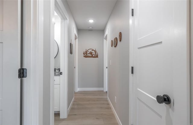 hallway featuring baseboards and light wood-style flooring