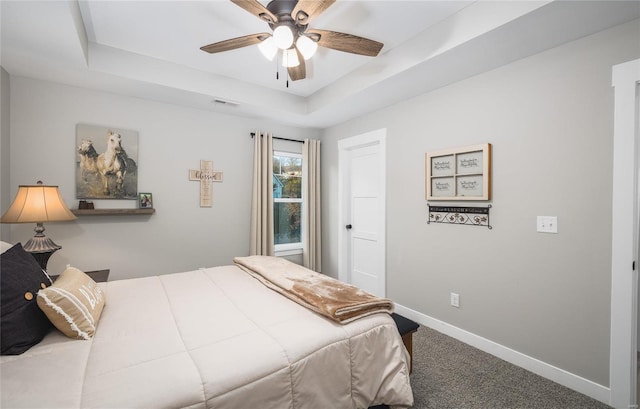 bedroom featuring carpet, baseboards, visible vents, a ceiling fan, and a tray ceiling