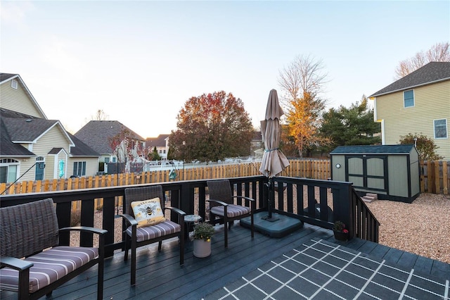 wooden deck featuring a storage shed, a fenced backyard, and an outdoor structure