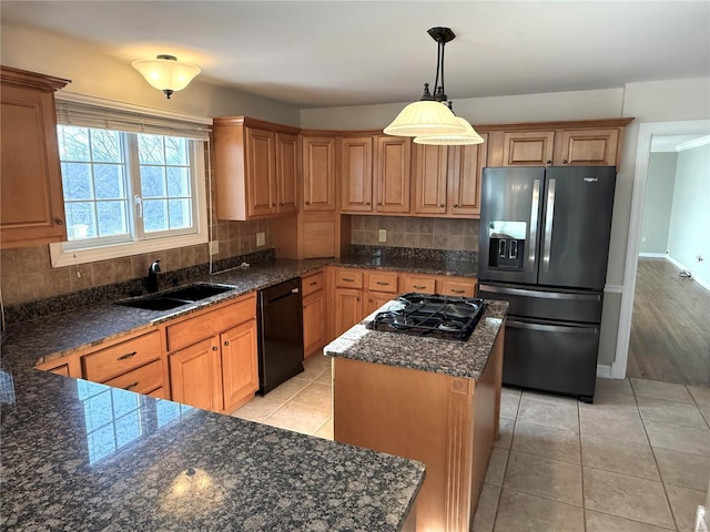 kitchen with sink, hanging light fixtures, black appliances, a kitchen island, and decorative backsplash