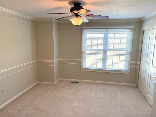 empty room with crown molding, light colored carpet, and ceiling fan