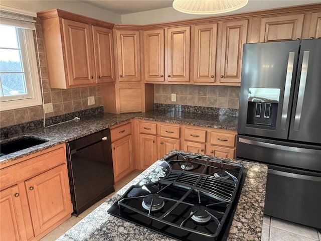 kitchen featuring tasteful backsplash, light tile patterned floors, black appliances, and dark stone counters