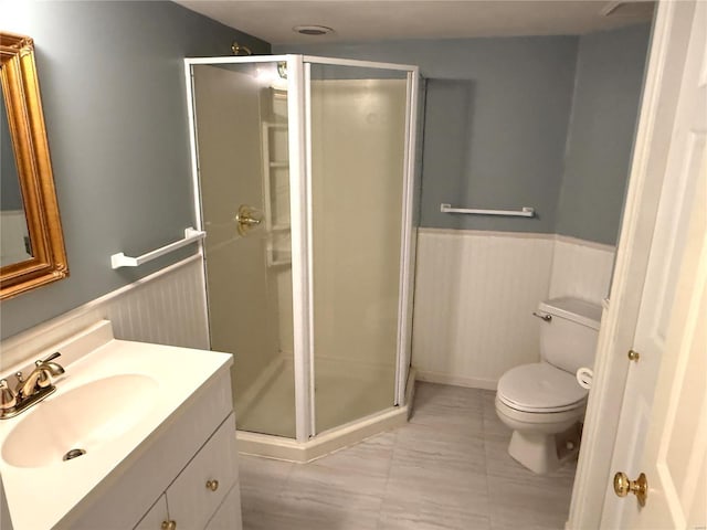 bathroom featuring vanity, toilet, and a shower with door