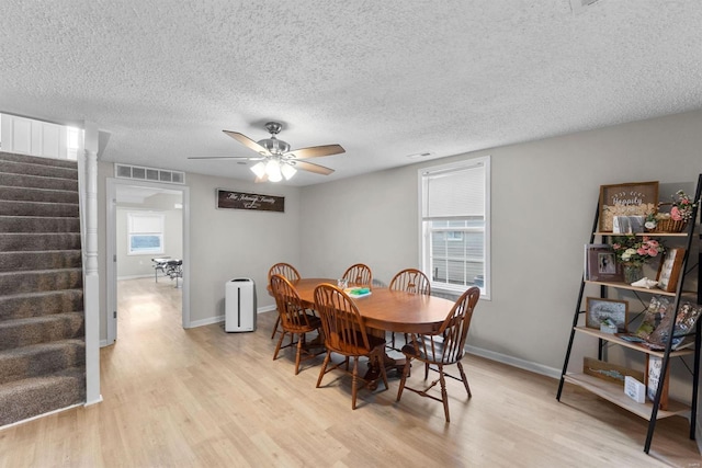 dining area featuring a textured ceiling, light hardwood / wood-style floors, and ceiling fan