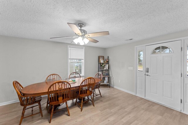 dining area with ceiling fan, light hardwood / wood-style floors, and a textured ceiling