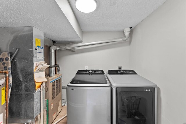 washroom with a textured ceiling, separate washer and dryer, and heating unit