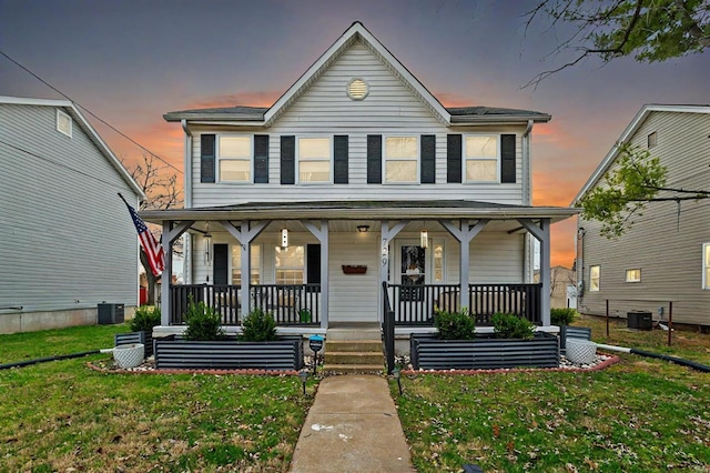 view of front of home with a lawn, central AC, and covered porch