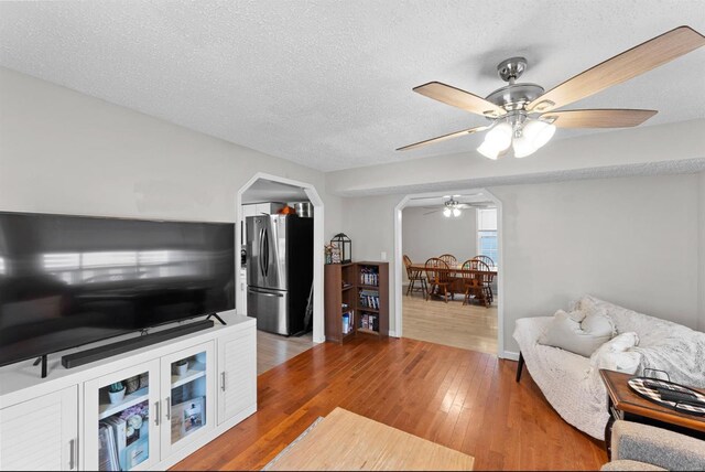 living room featuring ceiling fan, wood-type flooring, and a textured ceiling