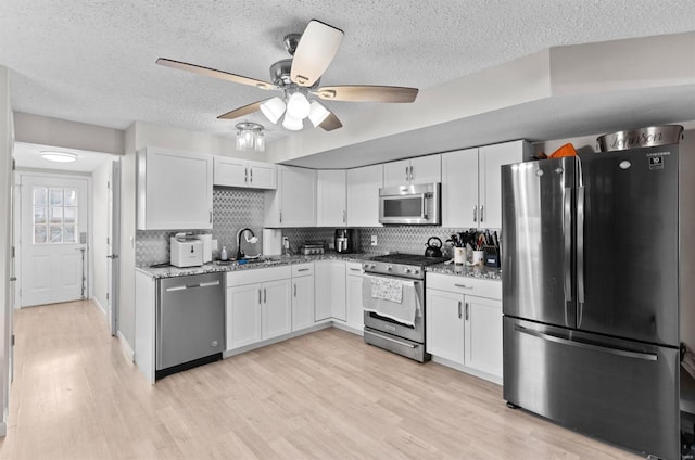 kitchen with white cabinets, appliances with stainless steel finishes, ceiling fan, and sink