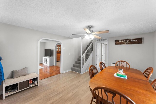 dining room with ceiling fan, light hardwood / wood-style flooring, and a textured ceiling