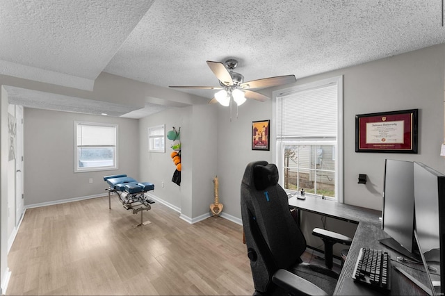 office area with ceiling fan, light hardwood / wood-style flooring, a healthy amount of sunlight, and a textured ceiling