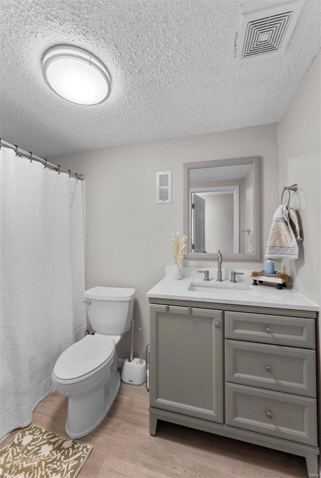 bathroom featuring hardwood / wood-style flooring, vanity, toilet, and a textured ceiling