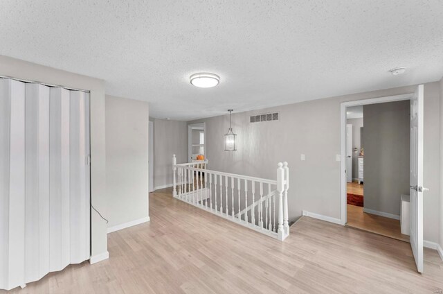 spare room with a textured ceiling and light hardwood / wood-style flooring