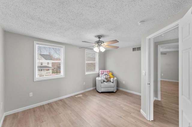 unfurnished room featuring ceiling fan, light wood-type flooring, and a textured ceiling