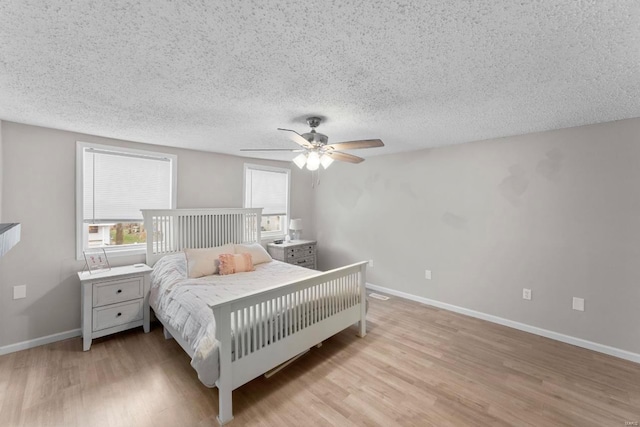 bedroom with a textured ceiling, light hardwood / wood-style floors, and ceiling fan