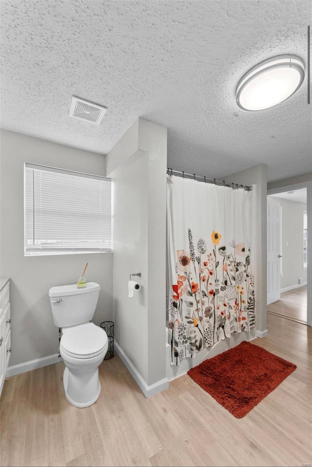 bathroom featuring a shower with curtain, hardwood / wood-style floors, a textured ceiling, toilet, and vanity