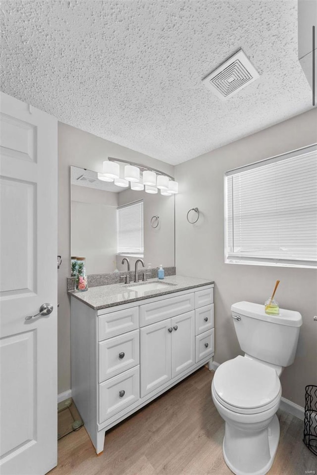 bathroom with vanity, toilet, wood-type flooring, and a textured ceiling