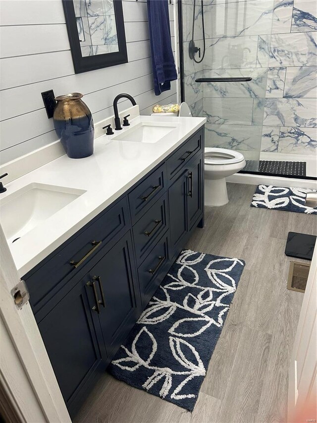 bathroom with vanity, tiled shower, hardwood / wood-style floors, toilet, and wood walls