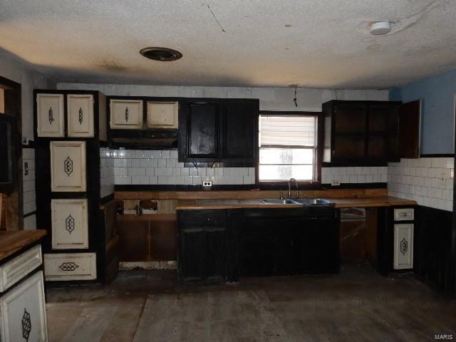 kitchen featuring a textured ceiling, sink, and tasteful backsplash