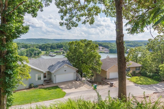 view of front of property with a front yard, a garage, and a water view