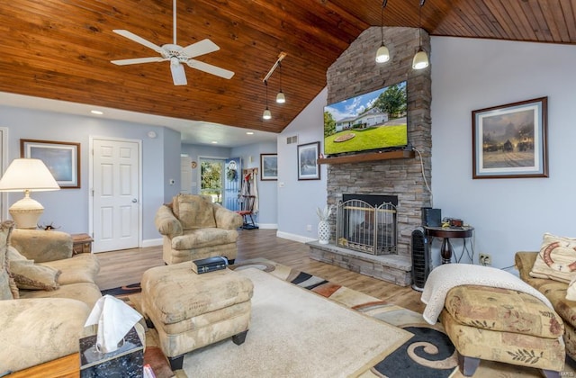 living room featuring lofted ceiling, ceiling fan, a stone fireplace, and wood ceiling