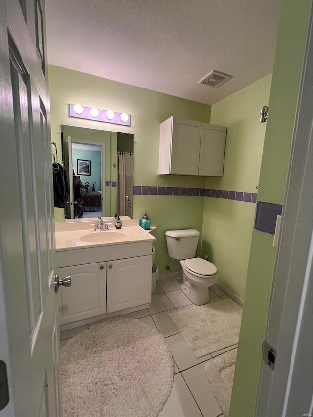 bathroom with tile patterned flooring, vanity, toilet, and a textured ceiling