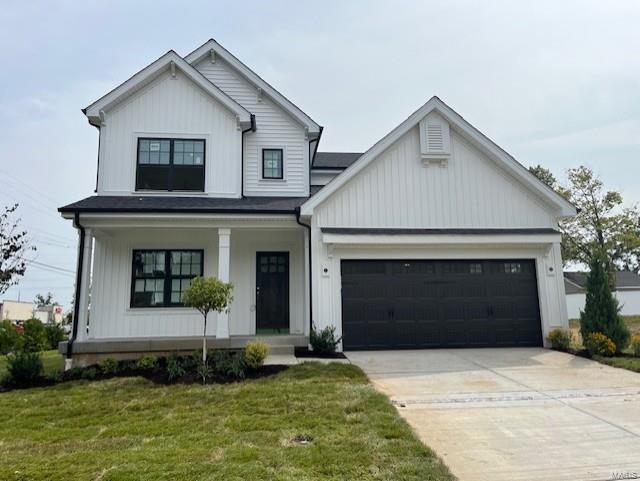 modern farmhouse featuring a garage, covered porch, and a front yard