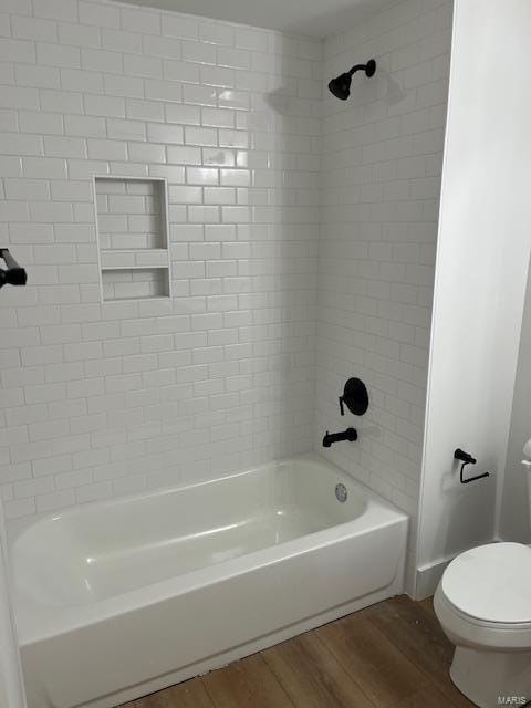 bathroom featuring tiled shower / bath combo, hardwood / wood-style floors, and toilet