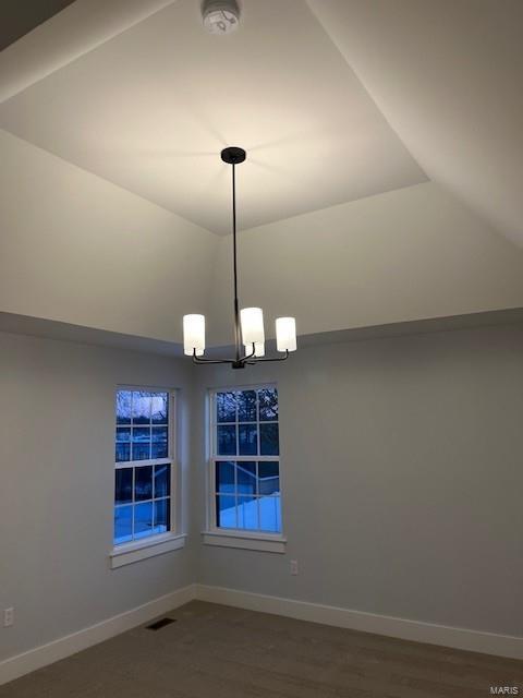 unfurnished dining area featuring a notable chandelier and vaulted ceiling