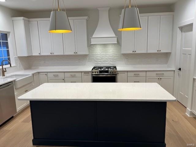 kitchen with custom exhaust hood, a kitchen island, decorative light fixtures, backsplash, and stainless steel appliances