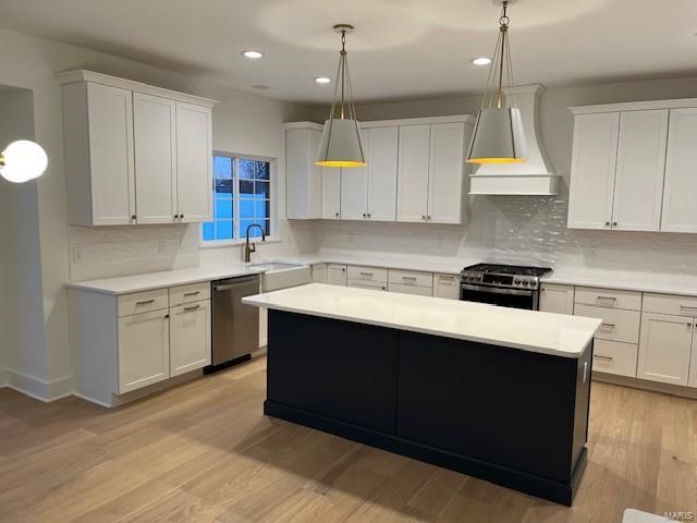 kitchen featuring premium range hood, white cabinetry, light wood-type flooring, pendant lighting, and stainless steel appliances