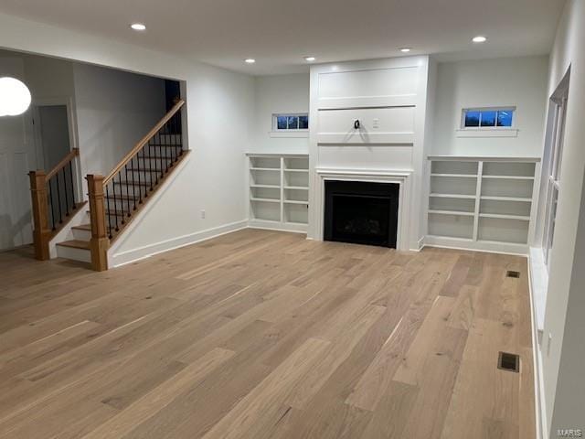 unfurnished living room with a large fireplace and light wood-type flooring